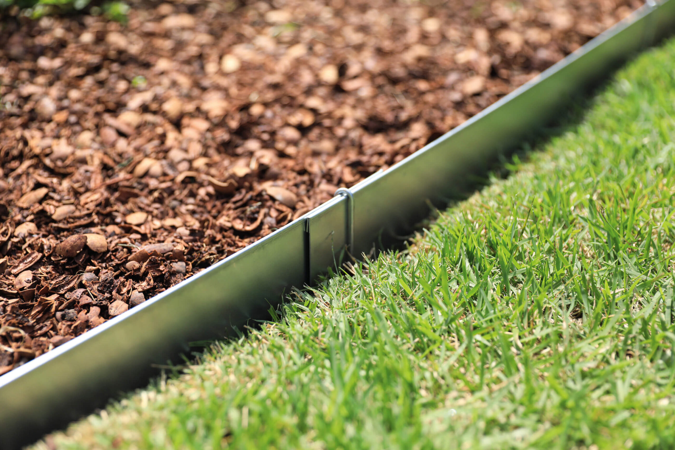 close-up of Place-and-Pin Steel Edging between mulch and grass